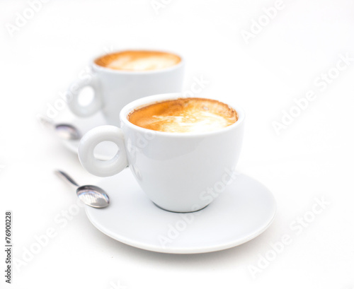 Two white cups of Cappuccino coffee with heart shaped milk foam