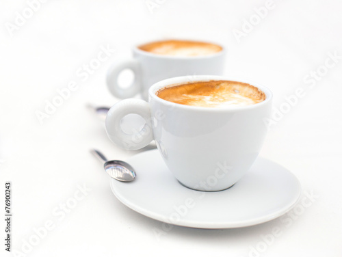 Two white cups of Cappuccino coffee with heart shaped milk foam