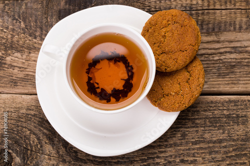 Image of ivory tea cup with sweet cookie on wooden palette