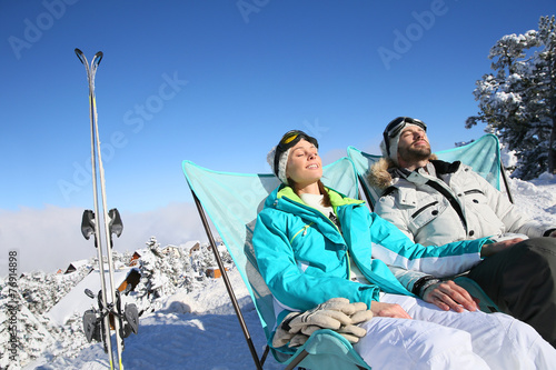 Couple of skiers sunbathing in long chairs