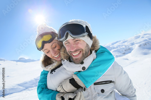 Man holding girlfriend on his back at the top of mountain