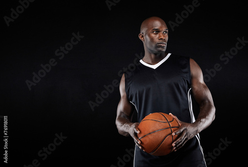 Muscular basketball player on black background