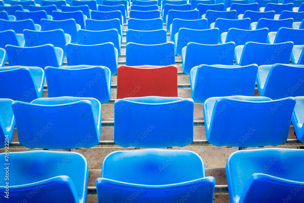 Fototapeta premium An empty red chair, arounded by blue chairs at the football Stad