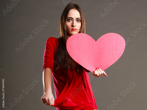 Woman in red dress holds heart sign