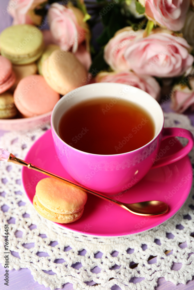 Colorful macaroons with cup of tea on wooden background Colorful macaroons with cup of tea on wooden background
