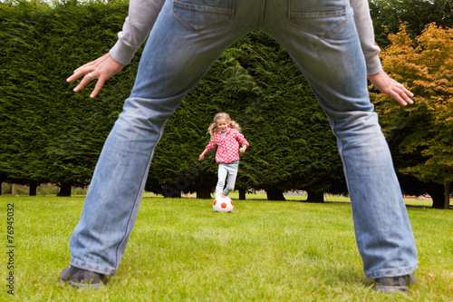 Father And Daughter Playing Football In Garden Together