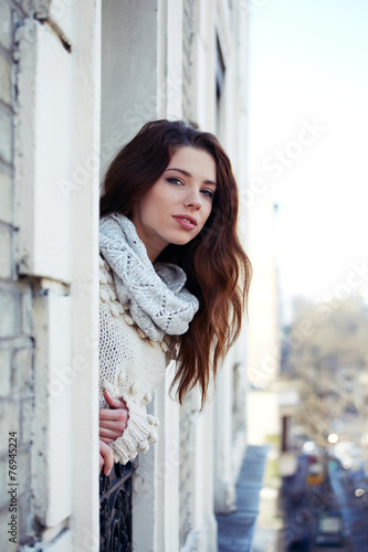 Young beautiful woman looks out the window at the city
