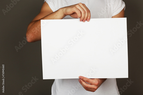 Blank sheet of paper in male hands on dark background © Africa Studio