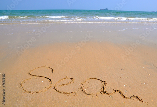 The word Sea is written on a sand background