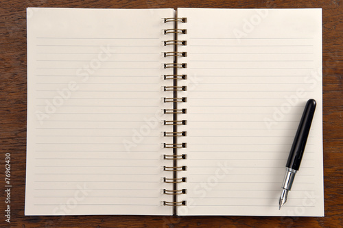 Open notebook and pen on wooden background.