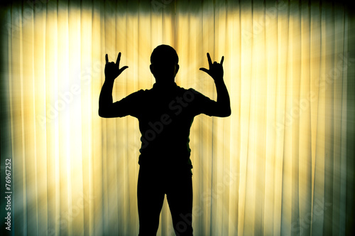 Silhouette man show his hands i love you sign with light ray eff