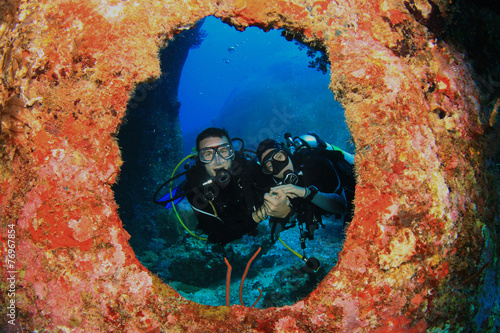 Scuba diving couple framed by coral