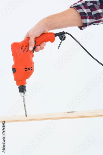 Male carpenter drilling hole in wood