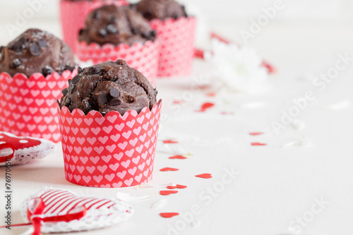 Chocolate muffin with red hearts on white background