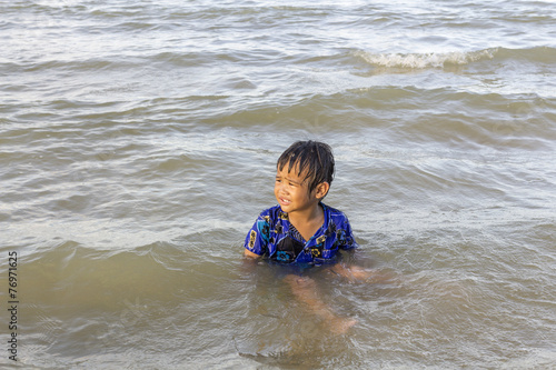 Child sitting in water sea © Suphatthra China