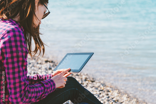 Woman sitting with digital tablet on beach