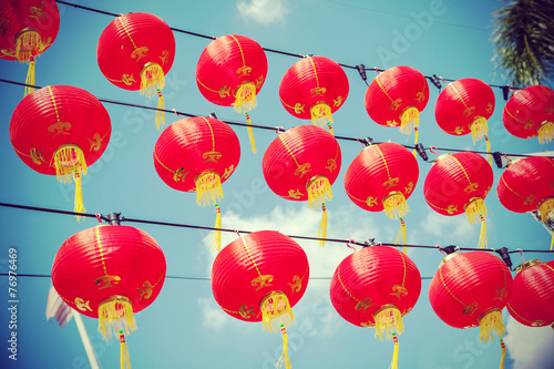 Retro filtered chinese red paper lanterns against blue sky.