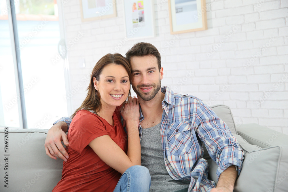Cheerful young couple relaxing in sofa at home