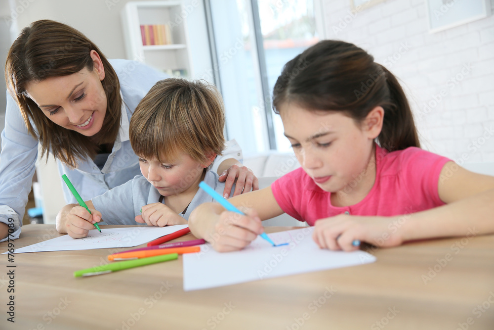 Mother watching kids at home while they are drawing Mother watching kids at home while they are drawing
