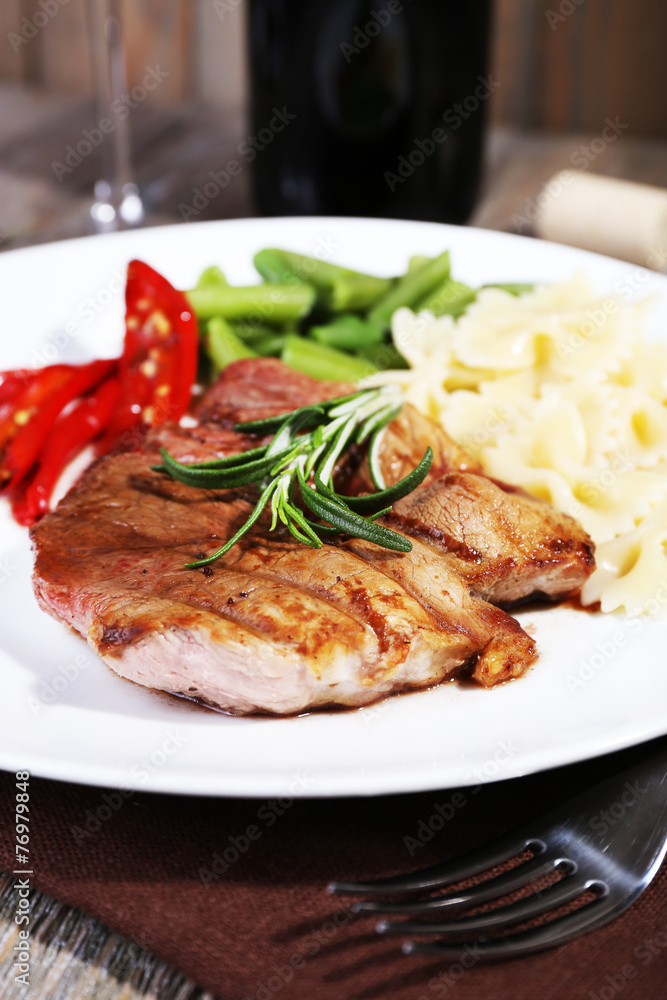 Steak with vegetables and pasta on plate on wooden plate Steak with vegetables and pasta on plate on wooden plate