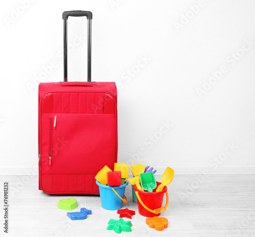 Red suitcase with child toys isolated on white
