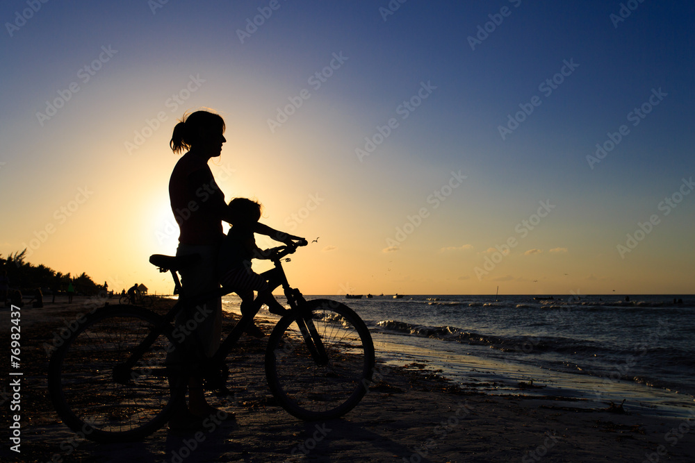 Fototapeta premium Silhouette of mother and baby biking at sunset