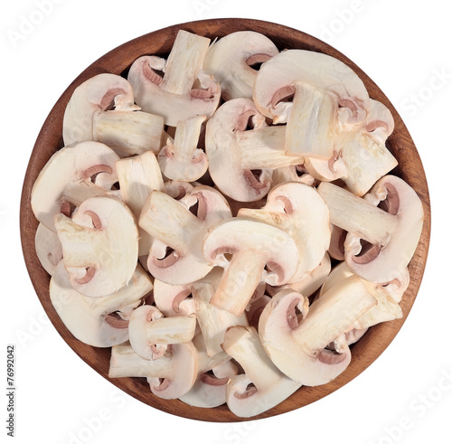 Sliced mushrooms in a wooden bowl on a white