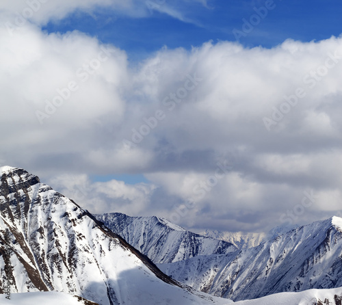 Winter snowy mountains in clouds at nice day