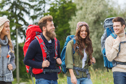 group of smiling friends with backpacks hiking