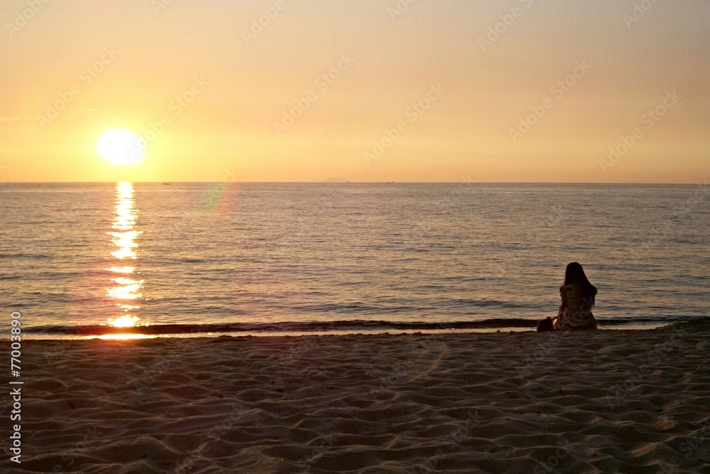 Girl sit alone on the beach to see sunset.