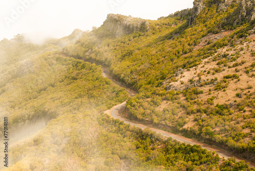 Winding road on a mountain side driving through the clouds.