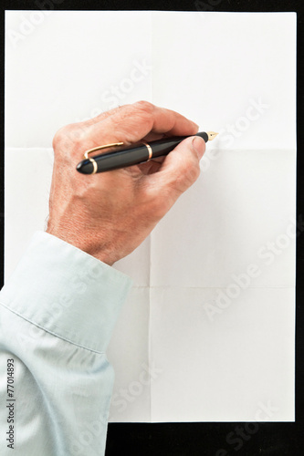 hand and pen write over sheet of paper