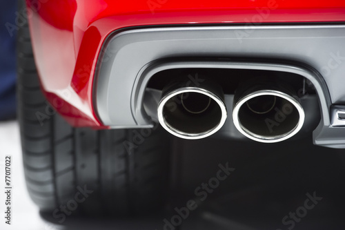 Chrome exhaust pipe of red powerful sport car bumper