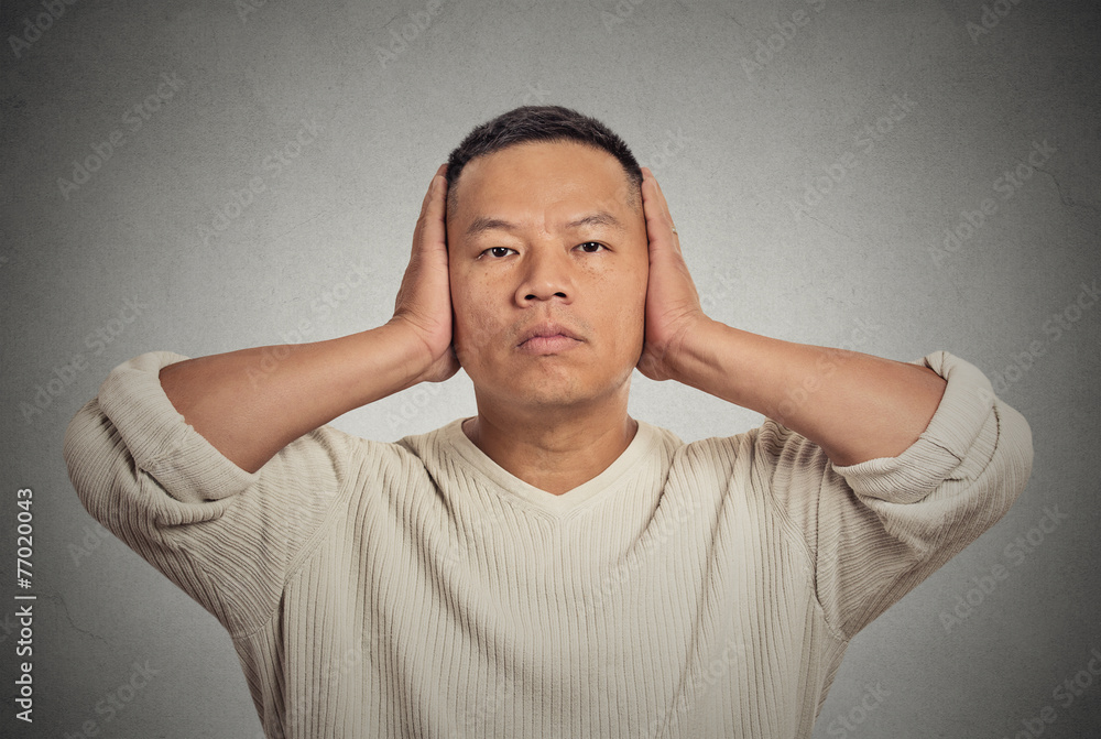 Middle aged man covering his ears observing avoiding noise Middle aged man covering his ears observing avoiding noise