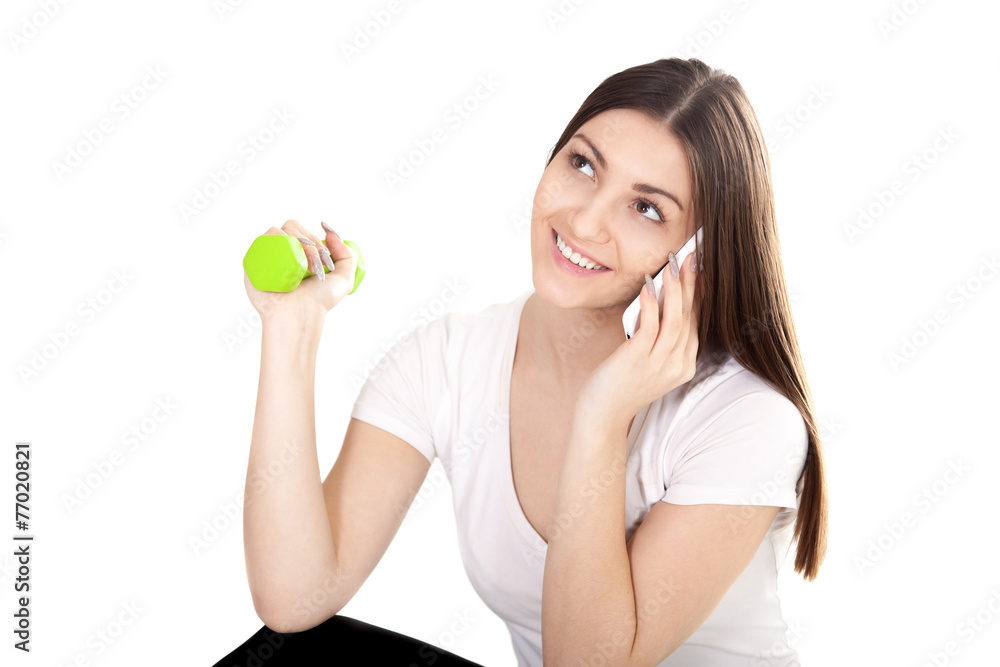 Smiling girl talking on phone and lifting green color dumbbells Smiling girl talking on phone and lifting green color dumbbells