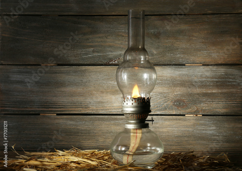 Schilderij op canvas Kerosene lamp with hay on rustic wooden planks background