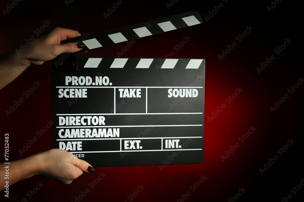Movie clapper in female hand on dark color background