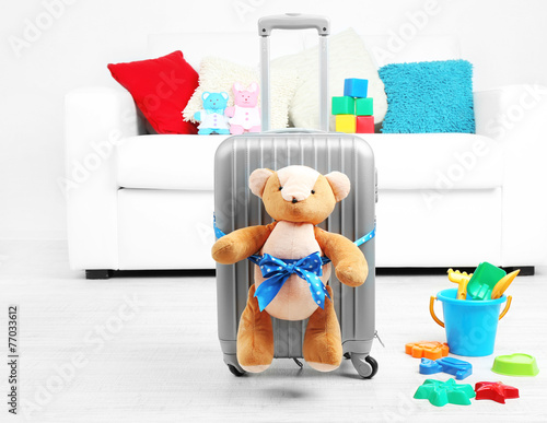 Suitcase with teddy bear and child toys in room © Africa Studio