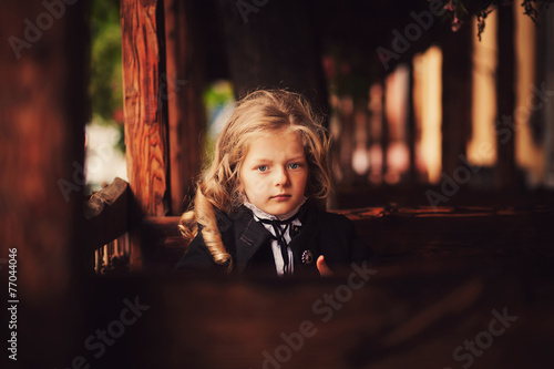 little girl sitting at a table in the street