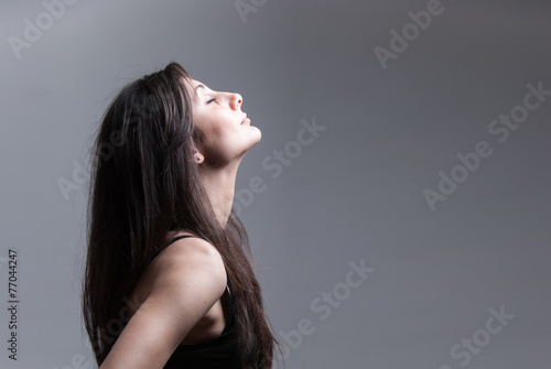 Side view of beautiful woman, looking up over dark background
