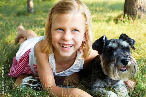 Cuadro en lienzo Cute little girl lying on the grass in the park, beside her dog
