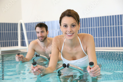 Couple in pool doing aquabike training © goodluz