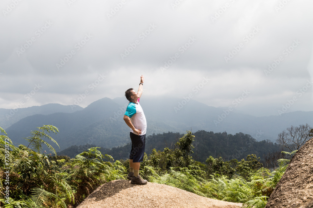 Obraz premium Man standing on the peak of a tropical highland forrest