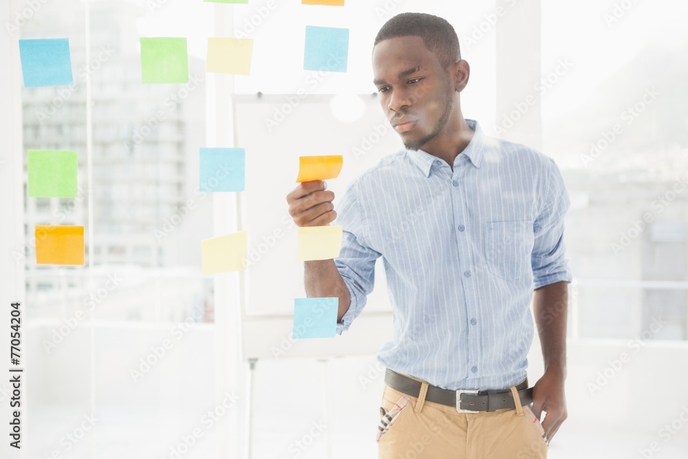 Casual businessman reading sticky notes on window Casual businessman reading sticky notes on window