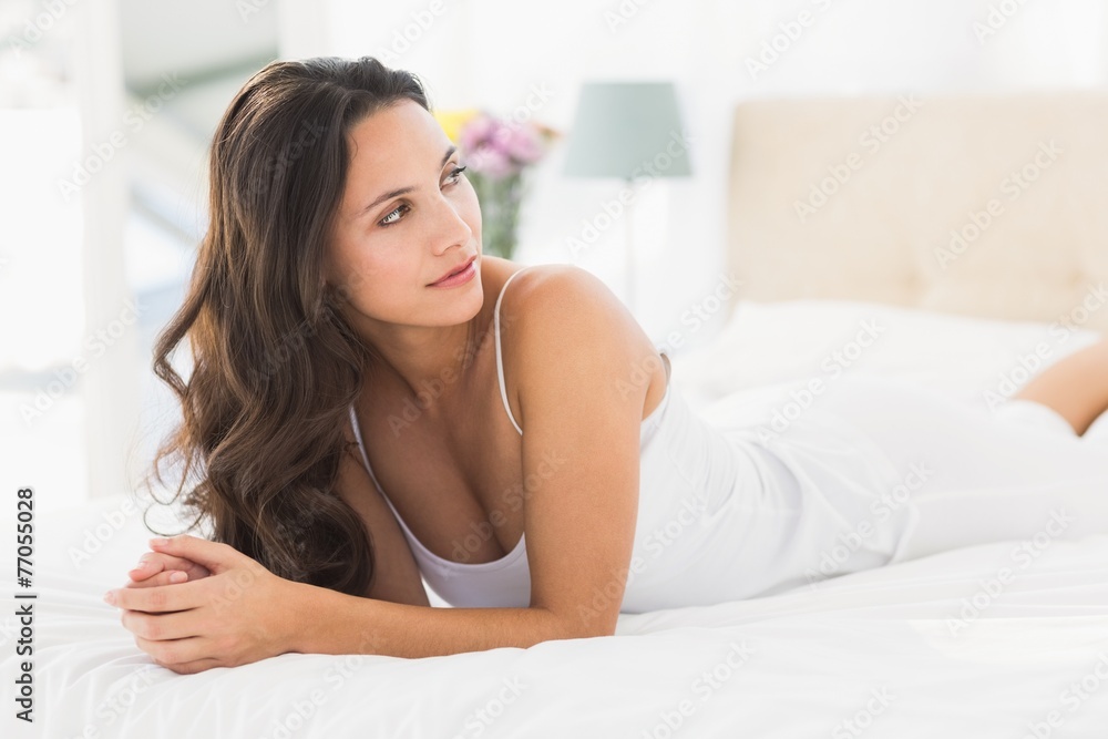 Happy brunette lying on bed