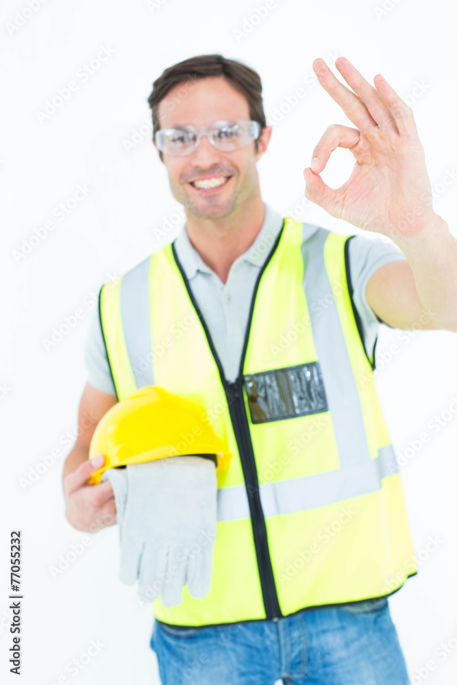 Carpenter holding gloves and hardhat while gesturing OK Carpenter holding gloves and hardhat while gesturing OK
