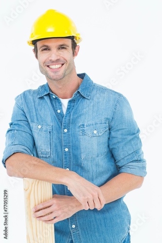 Happy carpenter leaning on wooden plank