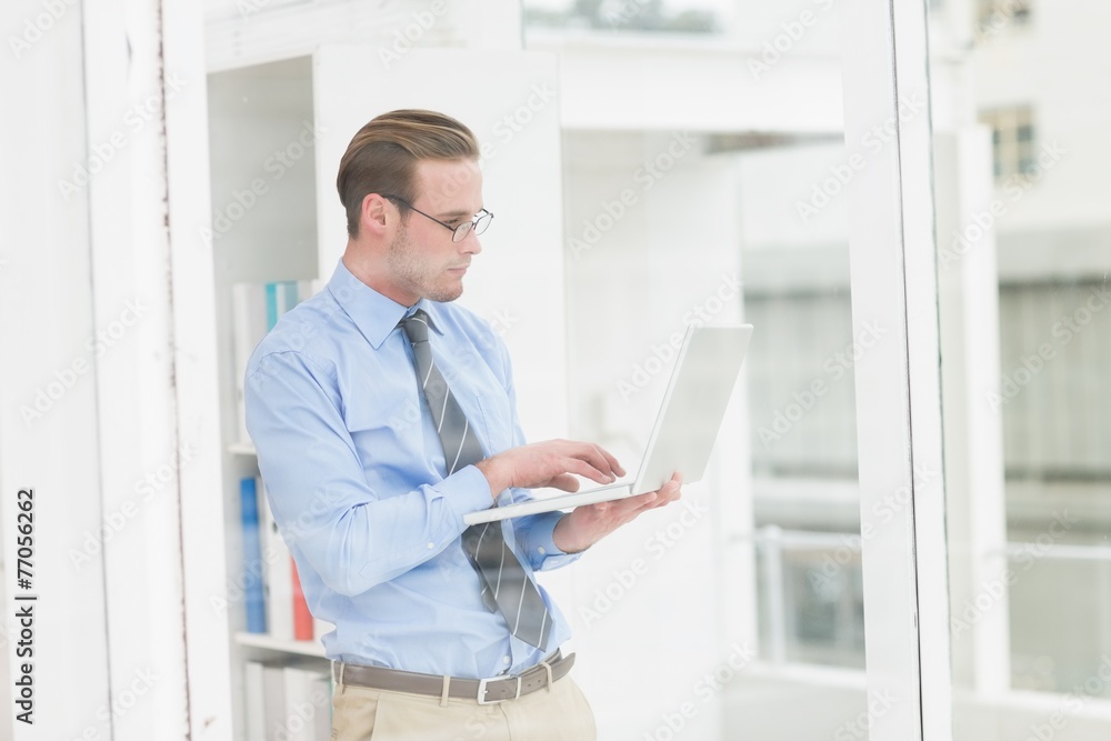 Focused businessman standing and using laptop