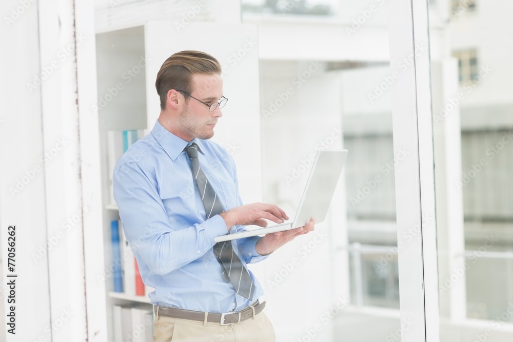 Focused businessman standing and using laptop Focused businessman standing and using laptop