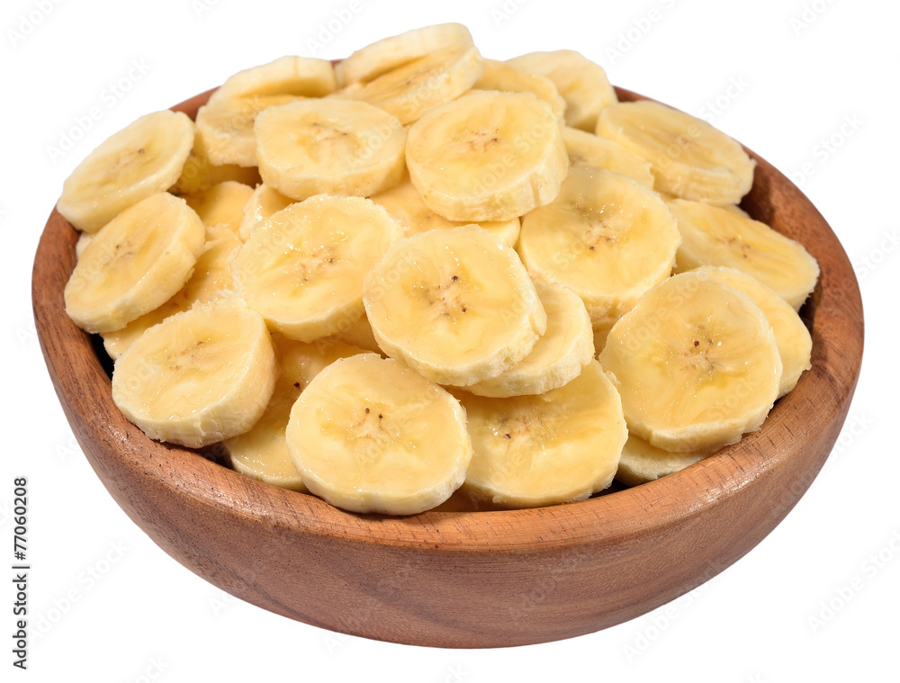 Banana slices in a wooden bowl on a white Banana slices in a wooden bowl on a white